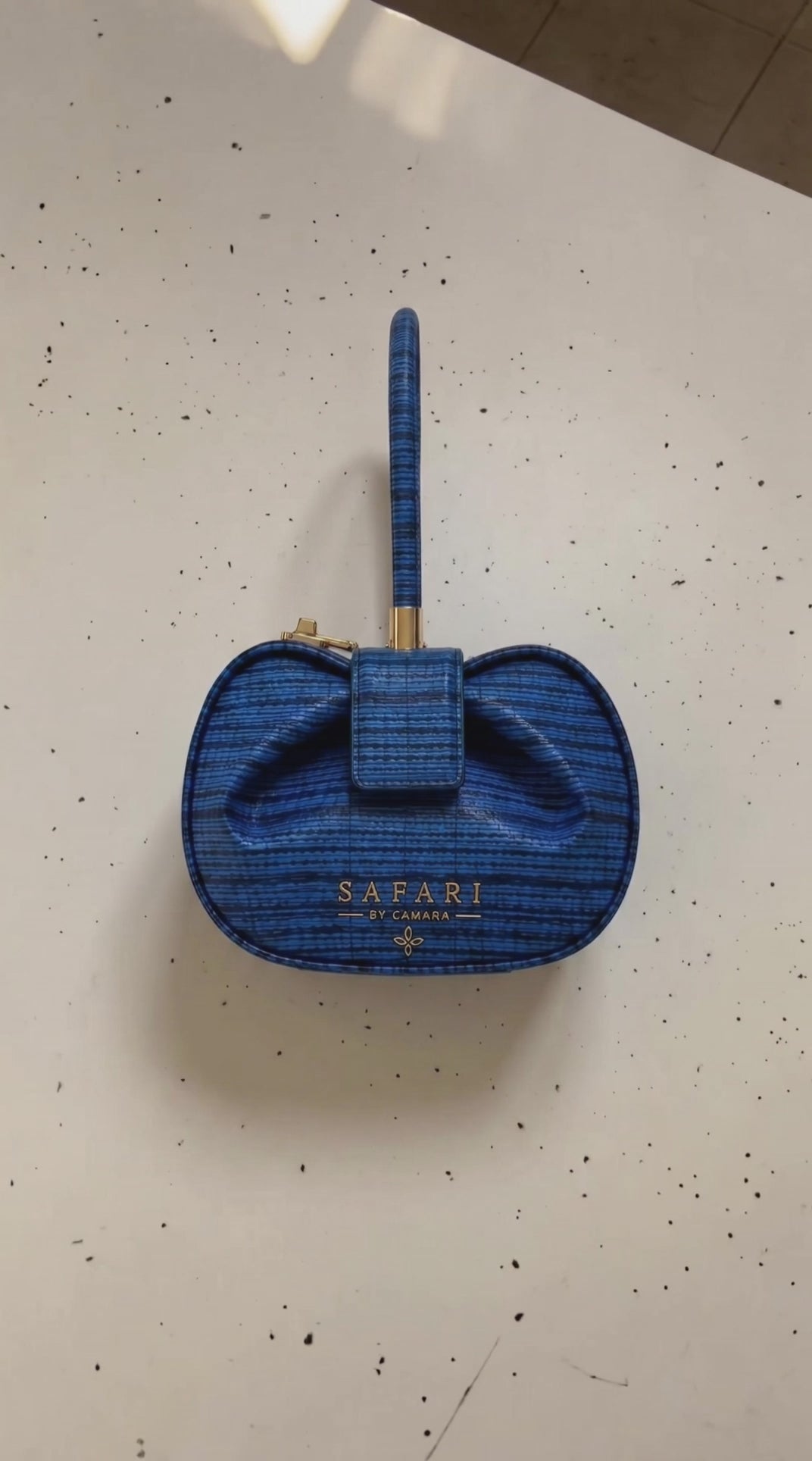 The Leppi blue leather handbags by Safari by Camara, featuring Leppi print-inspired blue and black textured patterns, sculptural bow detailing, and gold hardware.